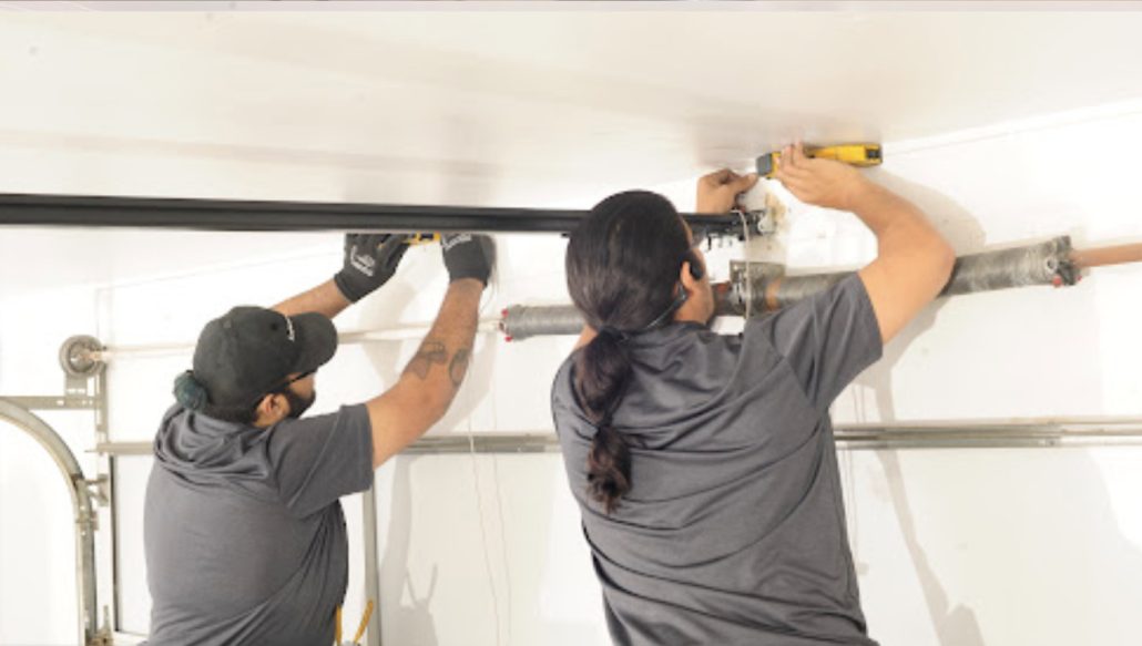 Two technicians working on overhead garage door hardware